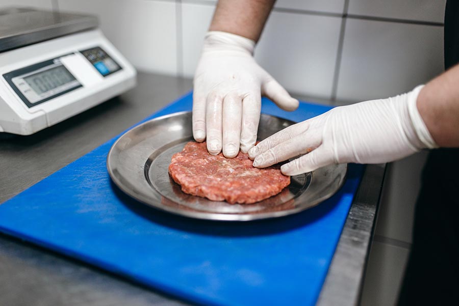 Chef hands in gloves prepares meat, burger cooking