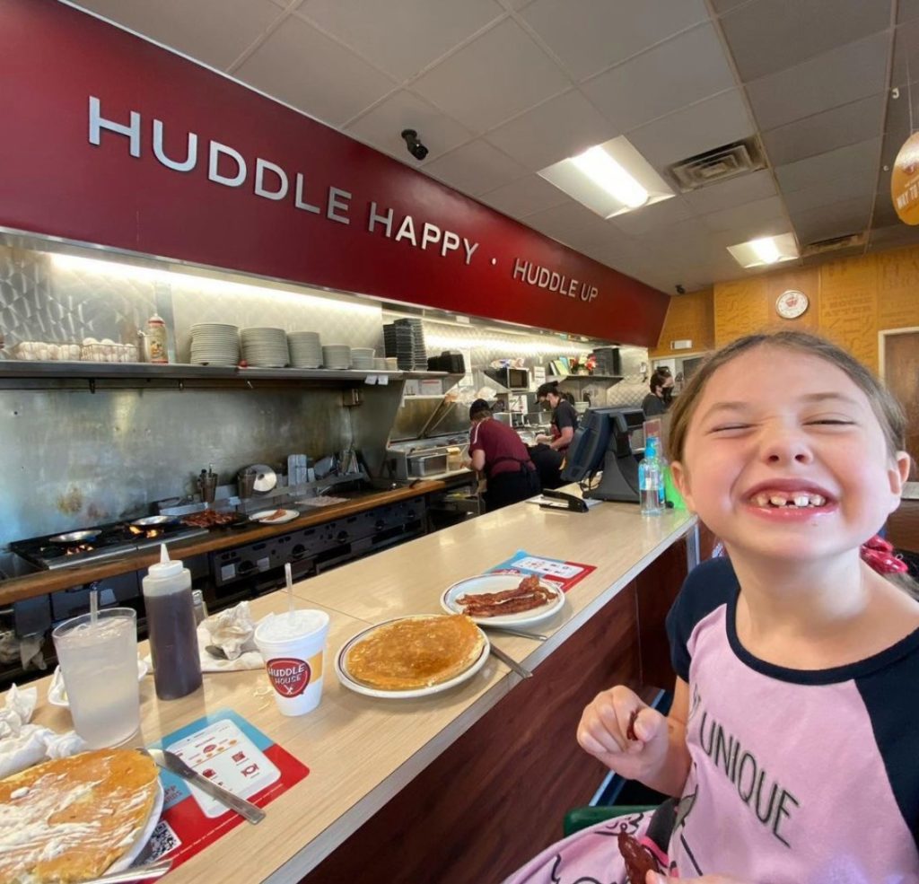photo of child grinning at Huddle House, a new nutrition client for MenuTrinfo