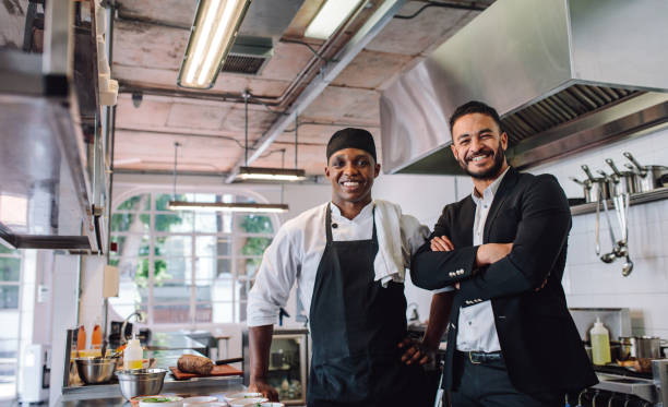 Owner and chef of a restaurant posing in the kitchen, smiling. 